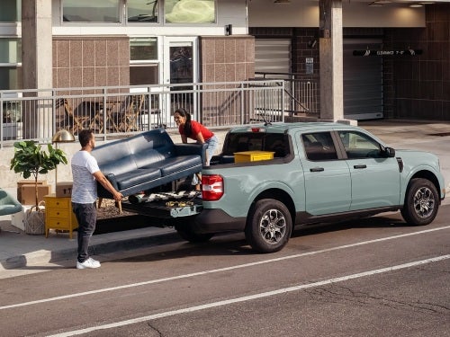 2024 Ford Maverick parked on the street while a couple loads the bed