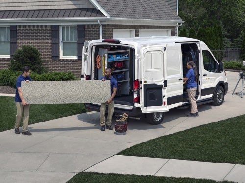 2024 Ford Transit parked outside a home while two men unload a slab of countertop out of van
