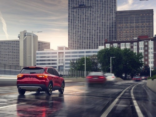 2024 Ford Escape Plug-in Hybrid driving into a city on a wet highway