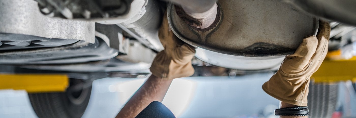 Close up view of a vehicle's catalytic converter being checked out by a service tech
