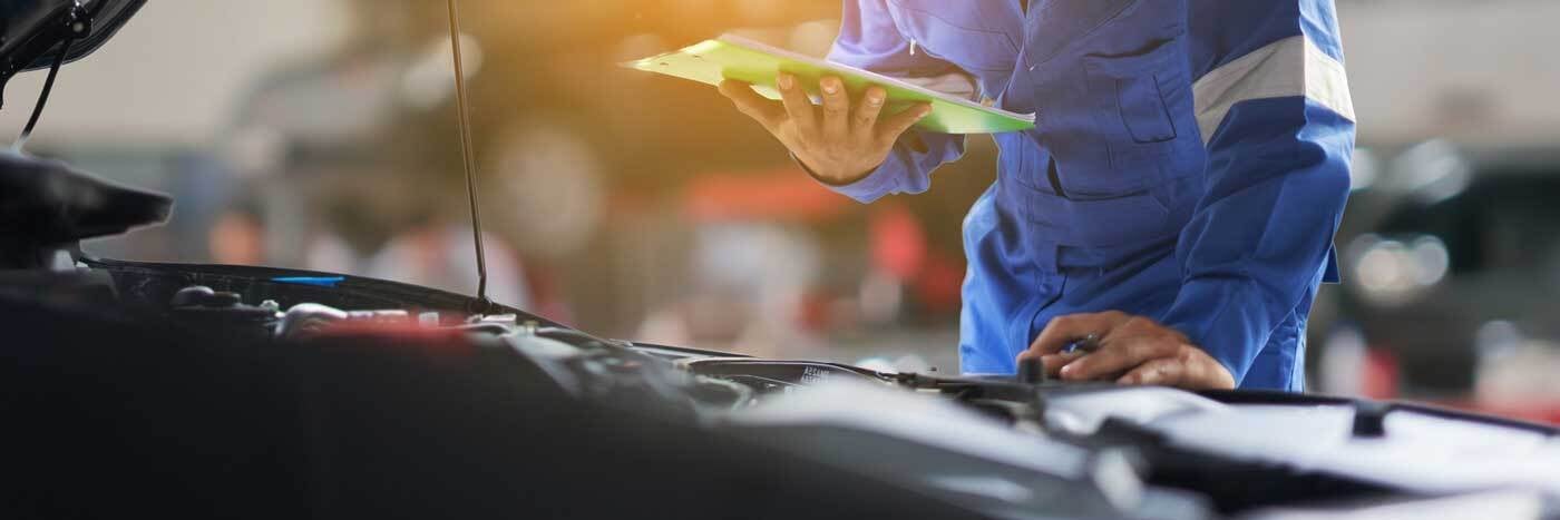 Close up view of a service tech inspecting a vehicle's engine